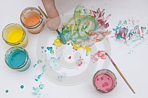 BabyÃ¢â¬â¢s hand with a brush and homemade paint. Homemade colorful paints for a baby in glass jars. Dough and food colorants. photo